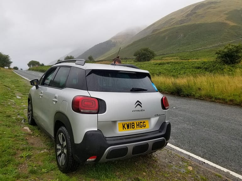 A rental car in the Scotland Highlands on a misty day showcasing a UK road trip