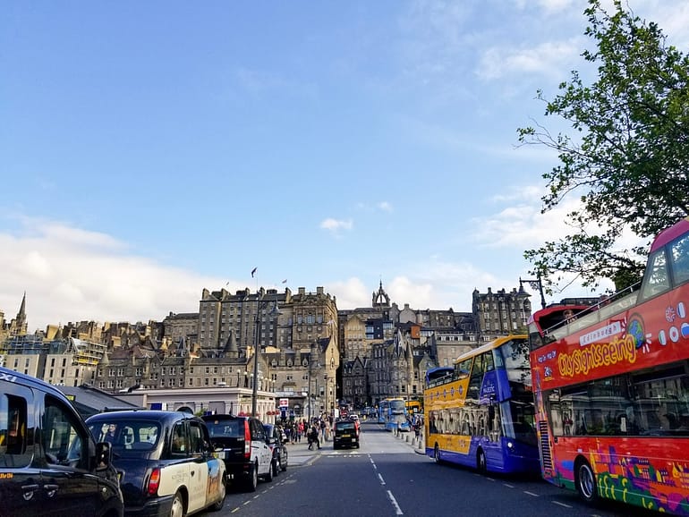 A photo of downtown Edinburgh showing the Edinburgh castle and a double decker bus hop on hop off bus in Scotland. A must do on a trip to Scotland